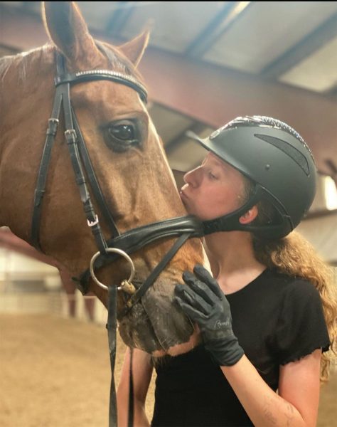 The young equestrian kisses her horse.