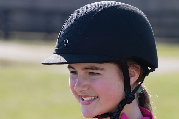 A young girl wears a correctly fitted riding helmet