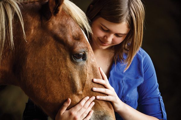 Young girl hugs senior horse