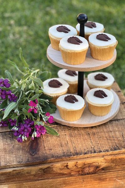 Horse-themed cupcakes on a table alongside purple flowers