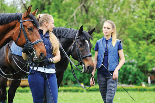 Two equestrians with their horses. Like anyone, they must overcome peer pressure.