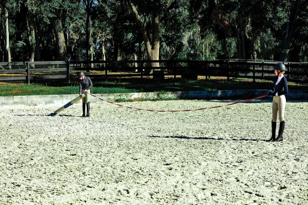 Eden and Madison use a longeline to measure distances to set up the circle of the ground pole exercise.