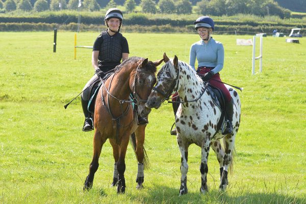 Two young riders each sit aboard a hony, which is a small horse