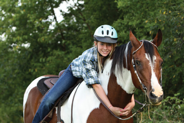 A young rider at camp. Learn how to avoid homesickness at horse camp with these tips.