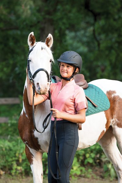 A young rider with her pinto pony
