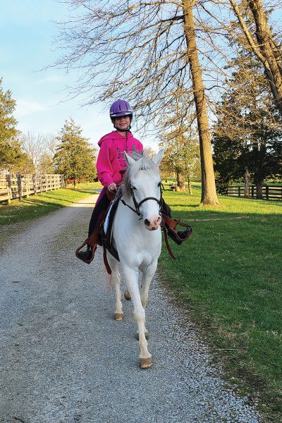 A young equestrian riding her pony, which she enjoys horsekeeping in the horse country of Kentucky