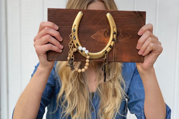 A young girl holds up a horse-inspired jewelry holder