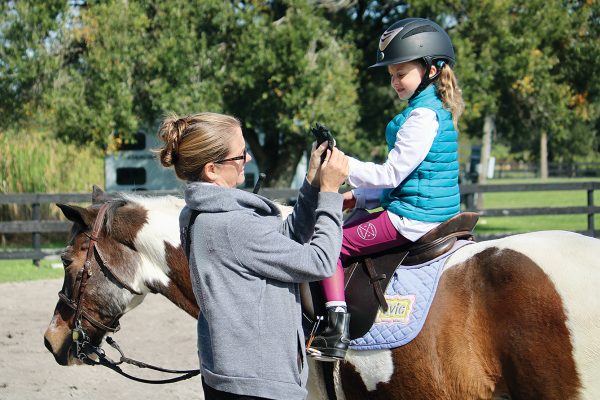 A young rider receiving help from her trainer.
