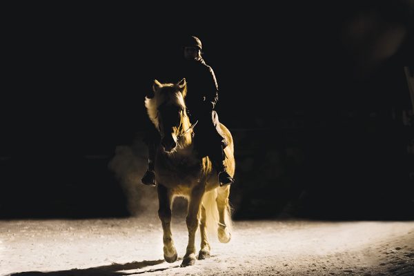 A girl rides her horse in the dark