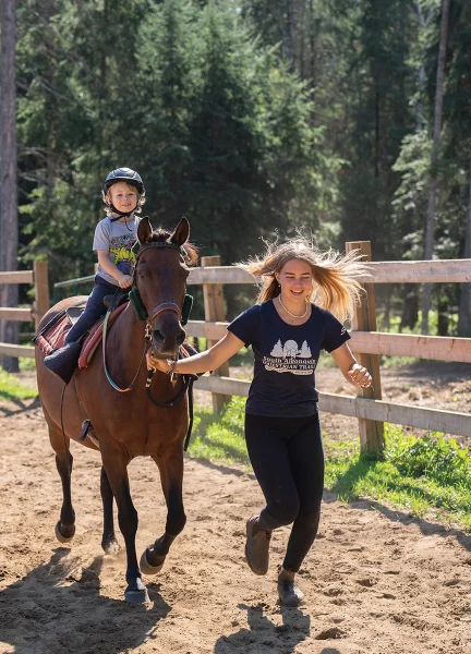 Ariella, the oldest sister, leads one of the campers at a trot.