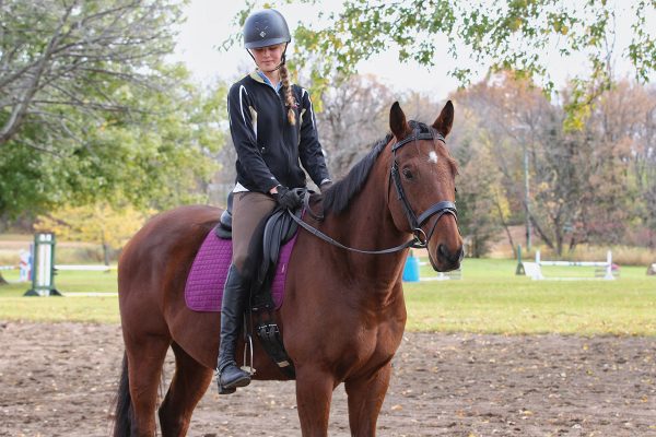 A young rider checks her stirrup length by making sure her ankle bone hits the stirrup bar with the irons dropped