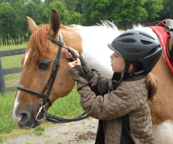 A young rider adjusts her bridle