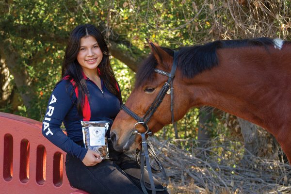 Mia Gabrielle Gonzales with a bag of her horse cookies brand, Caballo Cookies, and her pony