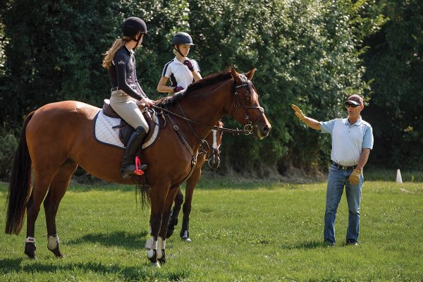 Young rider listens to experience trainer on cross-country course