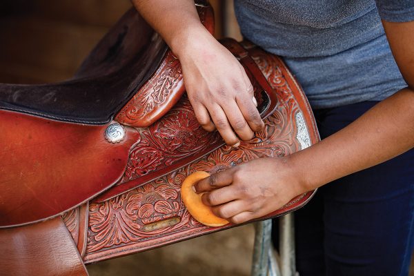 An equestrian cleans her saddle