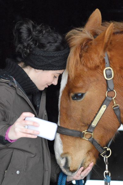 A girl snuggles with her pony while taking a picture
