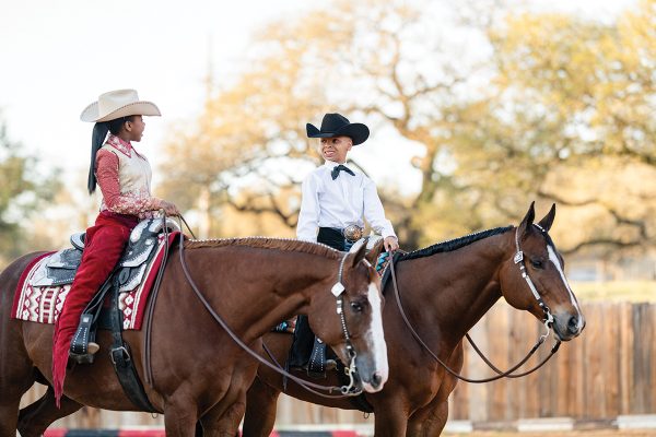 Two siblings riding together at a horse show