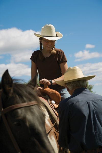 A young rider receiving help from her trainer.