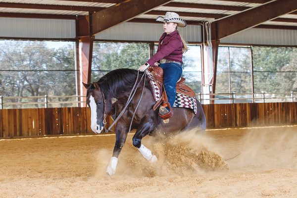 A young rider and her horse perform a sliding stop, one of reining's signature moves
