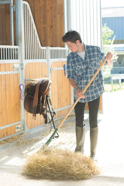 An equestrian tidying up the barn.