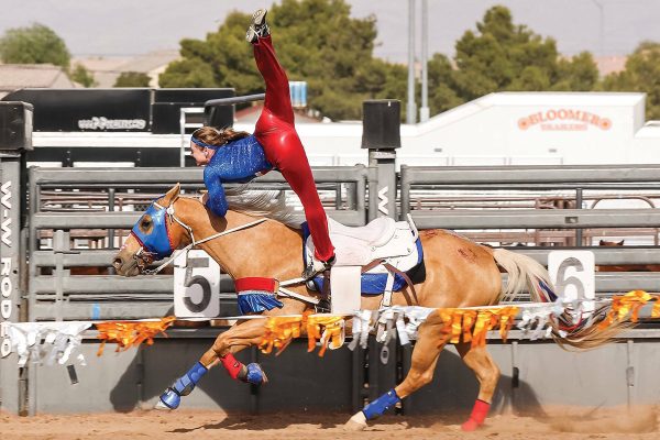 A girl trick riding on a palomino