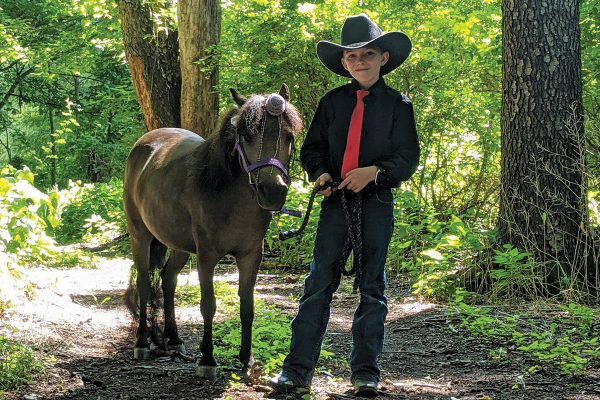 A young boy with his horse wearing a horn