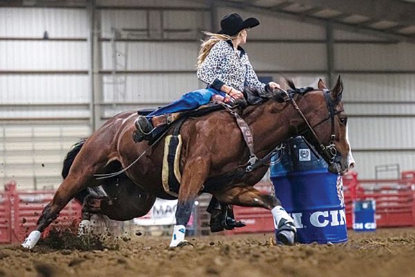 A cowgirl and horse barrel racing.