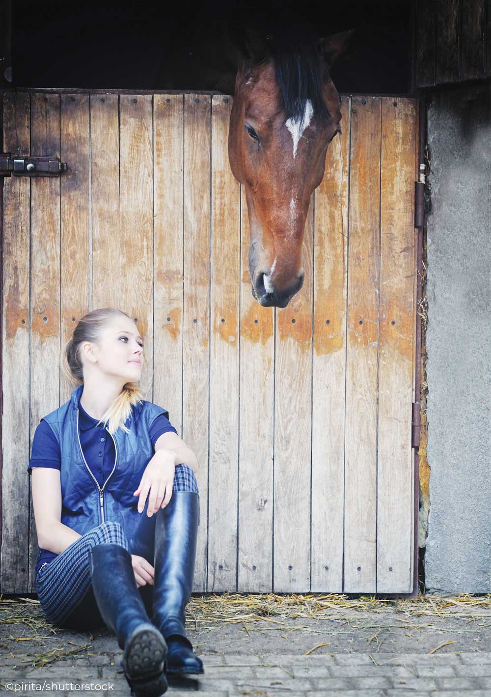 Girl sitting outside a horse's stall