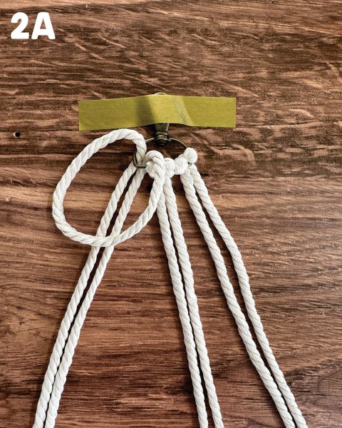Securing the DIY horsey keychain to a work surface with tape.