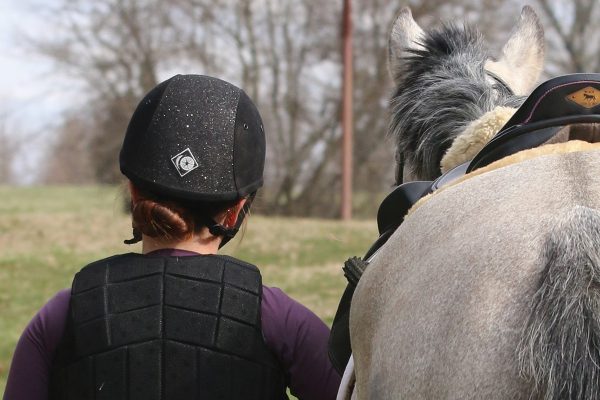 A young rider leads her horse away