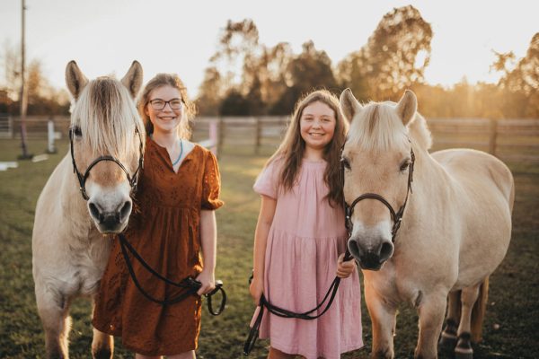 Two young girls pose with their ponies