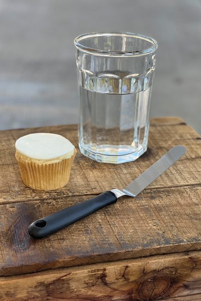 A dessert alongside an icing spatula and a glass of water