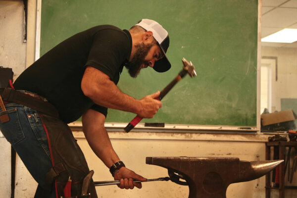 An instructor at a horseshoeing program performing an example for students
