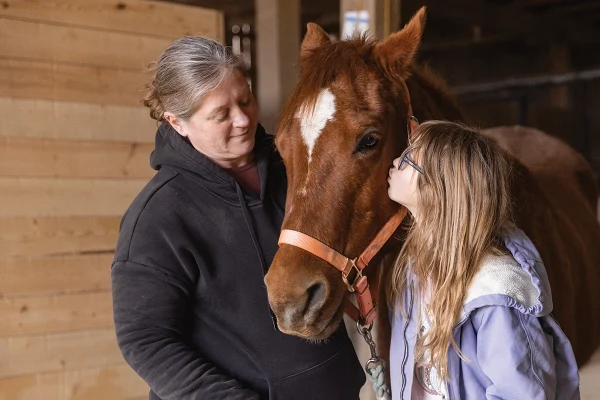 A family welcoming a horse they brought home via adoption.