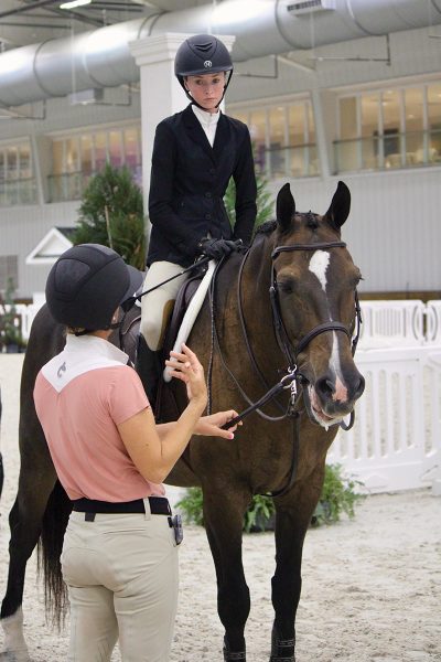 A trainer talking with her student at a horse show.