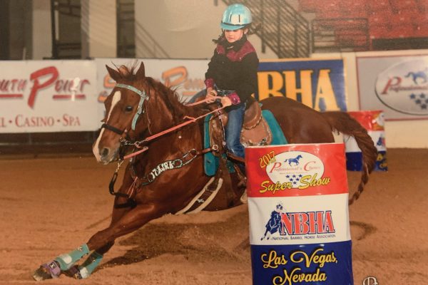 A young girl competing in barrel racing