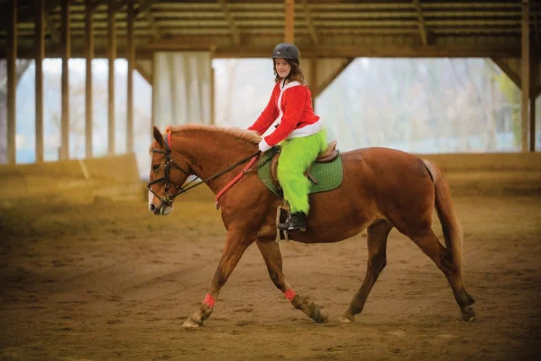 Zoie riding Izzy in a Grinch costume.