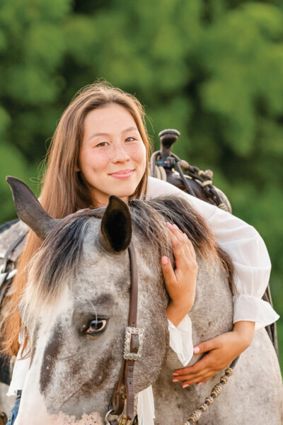 A young rider hugs her pony