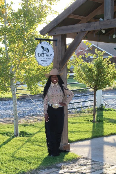 Standing below the Moose Tracks Therapy Ranch sign.