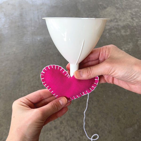 Using a funnel to fill a DIY hand warmer with ice