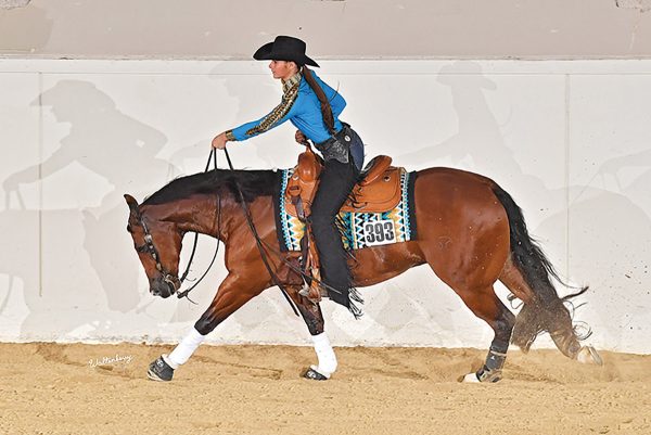 A youth rider wearing dark-colored chaps in the reining pen, her preferred apparel for the western event.
