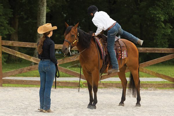 A young rider shows how to dismount a horse.
