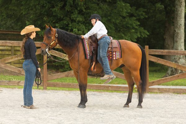 A young rider safely gets out of the saddle.
