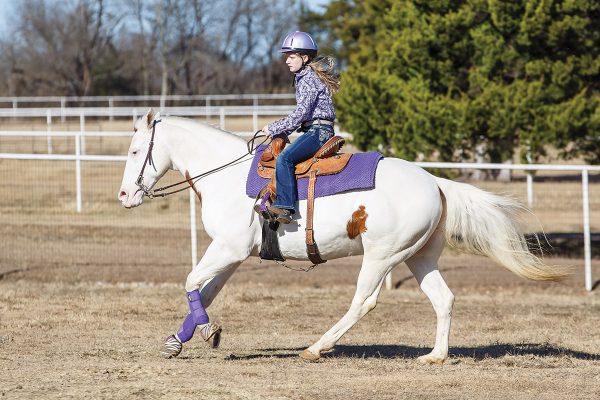 A young girl rides her horse at the extended lope