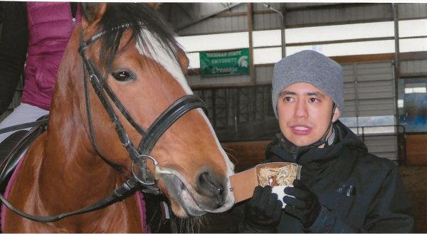 Alex showing a horse his miniature replica, made via his Alex's Clay Creations business.
