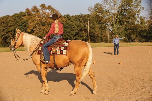 A young rider listens to instructions from her trainer