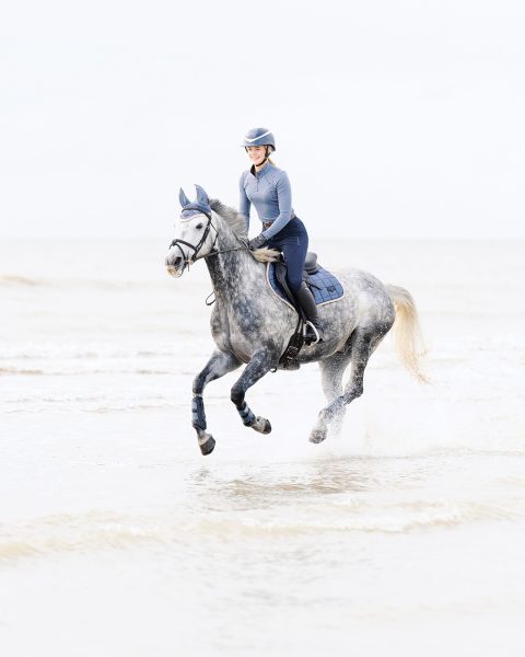 Esme riding her horse on the beach.